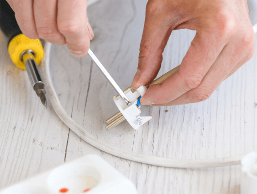 electrician repair man hands spin tighten screws with screwdriver small plastic european extension plug cord power strip close up 1 min